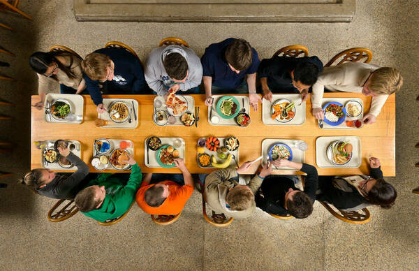 Overhead image of 12 students at a rectangular long table with plates on them