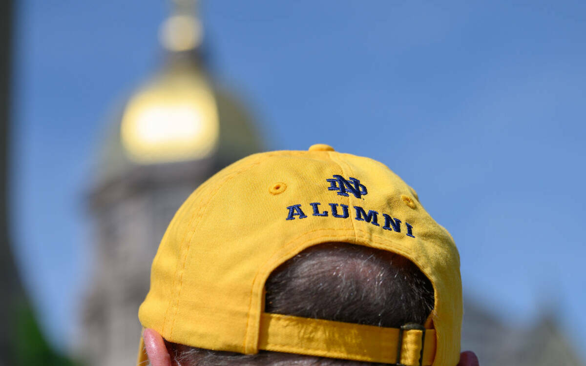 Back of a gold baseball cap that says "alumni" with the interlocking ND logo