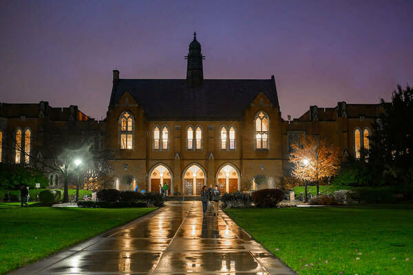 South Dining Hall building at night with lights reflecting off puddle on sidewalk