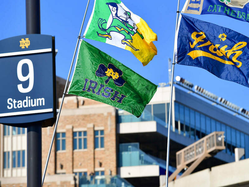 Stadium parking row 9 with 4 flags with the Notre Dame Leprechaun and Irish at Gameday Tailgates