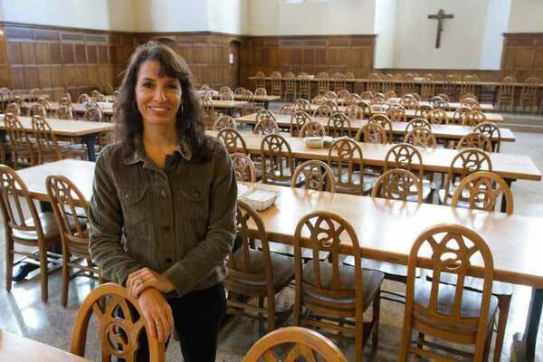 Image of a brunette woman in front of table and chairs in South Dining Hall