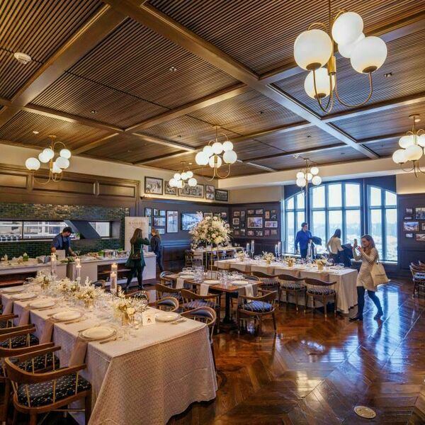 Foley's event space decorated for a wedding. White tablecloths and white place settings sit atop long tables. Wooden chairs rest along the tables.