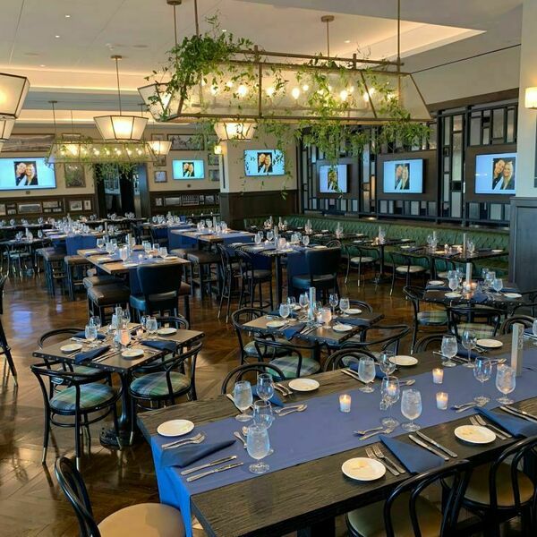 Foley's event space decorated for a wedding. Greenery hangs from the lights and blue place settings sit atop the tables.