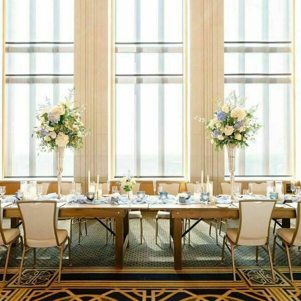 Dahnke Ballroom bride and groom table in front of big windows for a wedding. Large white and blue flower bouquets sit atop the table.