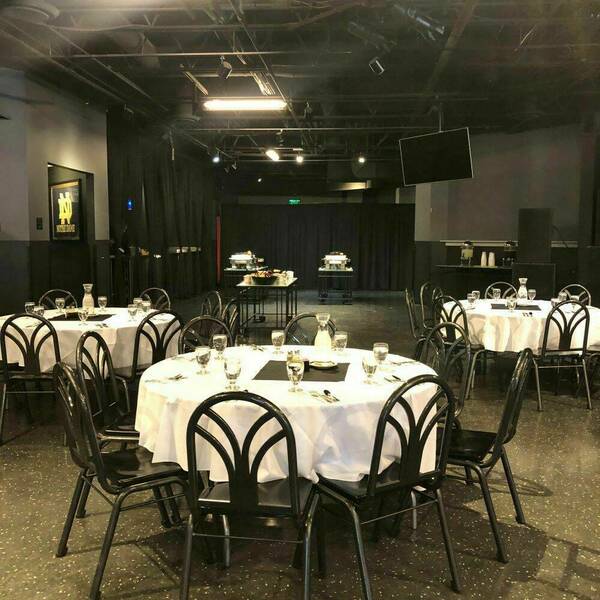 Legends event space decorated with tables and white tablecloths for an event.