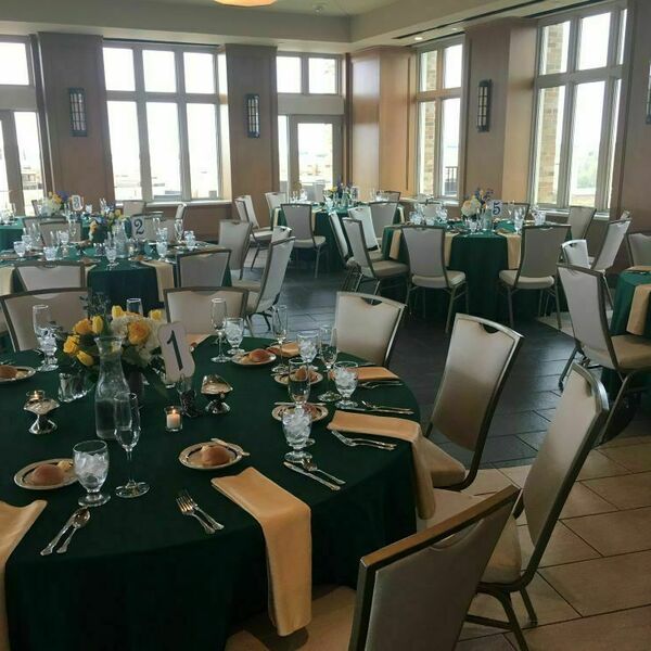 Landing Event Space decorated with dark green tablecloths and gold touches.