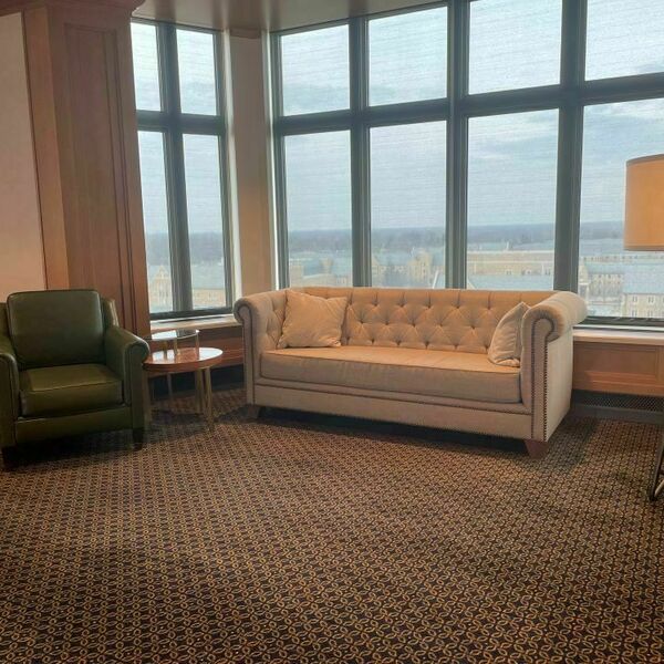Hank Family Forum event space with a cream colored couch and a dark green armchair in front of large windows.
