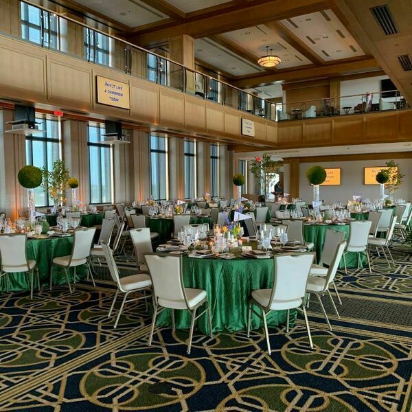 Downes Club event space decorated for an event. Decorations include tables with dark green tablecloths, candles and faux greenery balls.