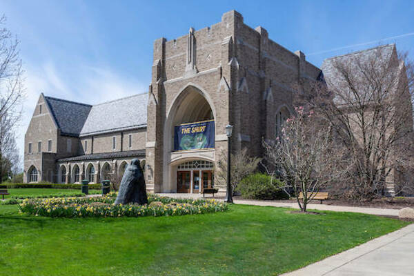 The bookstore on a sunny, spring day. A statue with a ring of tulips stands in front of the entrance to the library.