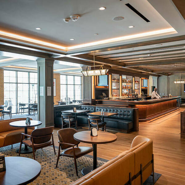 Wide view of Rohr's main dining room. Tables and chairs fill the room and a long bar sits in the middle.