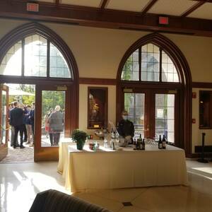 Large wooden doors with curved windows open to the patio. A bar sits right in front of the doors and guests enjoy drinks outside.