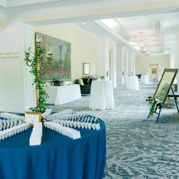 Outside of the Smith Ballroom at Morris Inn decorated for a wedding. A blue table with name cards and a welcome sign welcomes guests in.