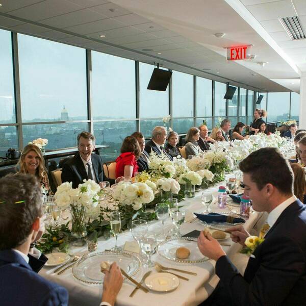 Wedding guests sit around a long rectangular table. A view of the stadium and Golden Dome can be seen in the back.