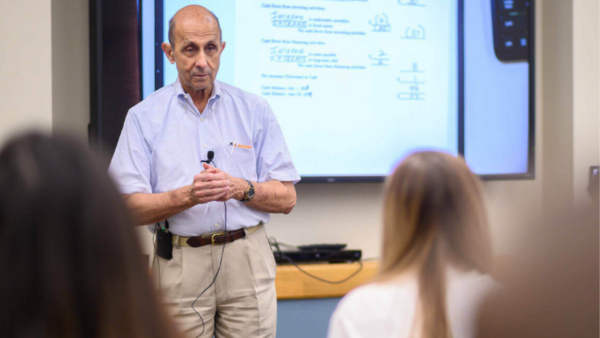 Professor Ken Milani stands at the front of a classroom teaching a lesson to students.