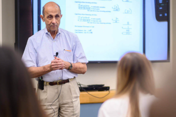 Professor Ken Milani stands at the front of a classroom teaching a lesson to students.
